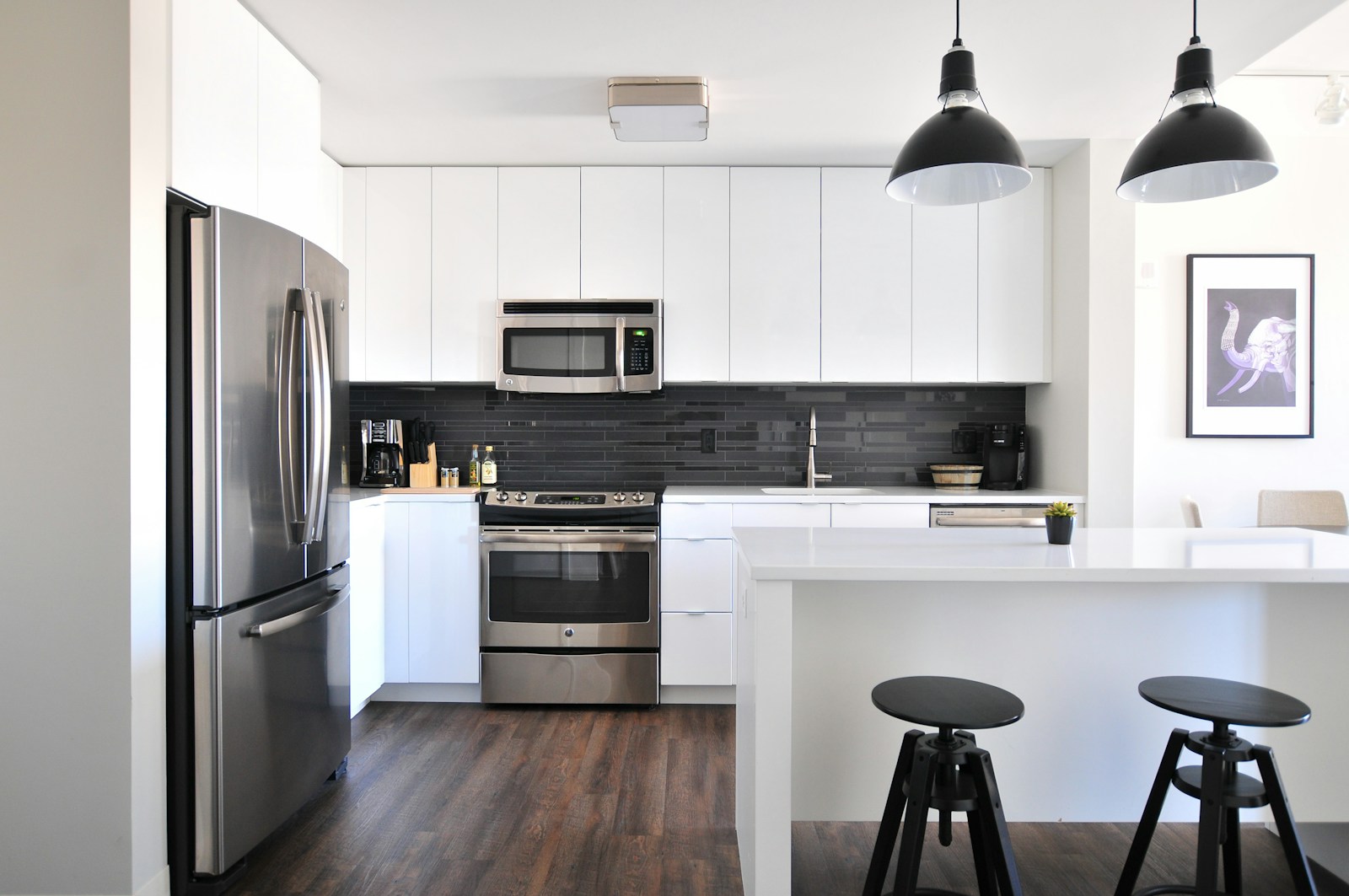 Finished kitchen with white cabinetry, a white island and dark wood flooring